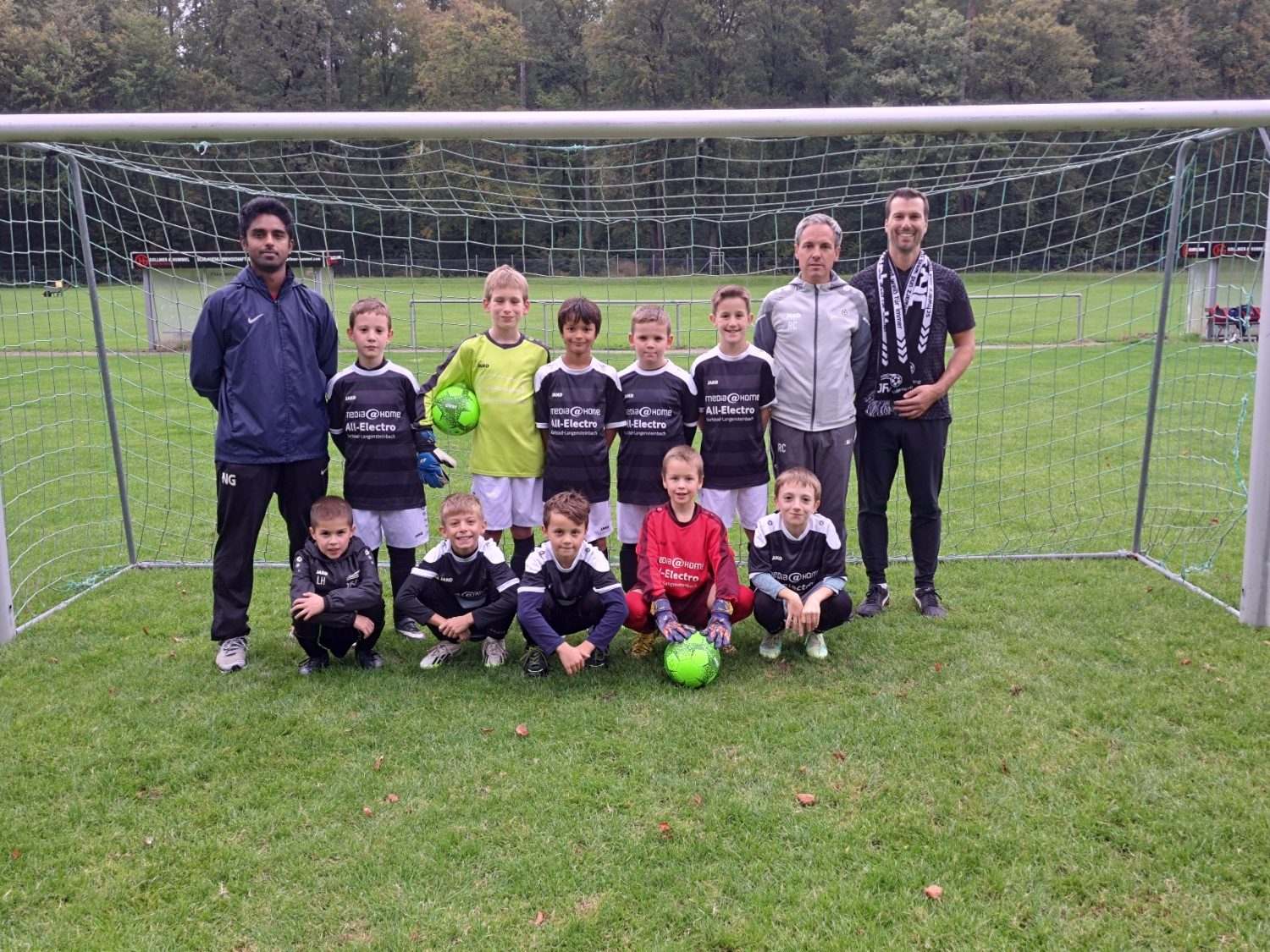 Kinder stehen lächelnd vor einem Fußballtor und posieren für ein Gruppenfoto.
