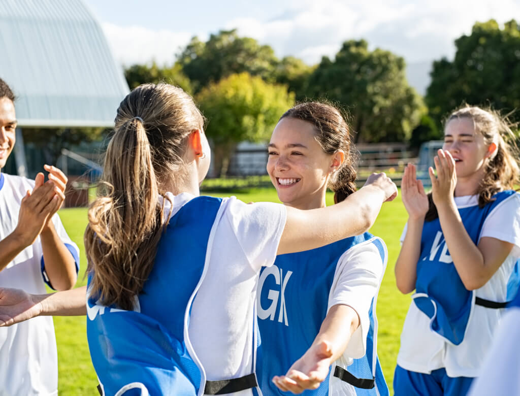 Eine Gruppe junger Frauen in blauen Uniformen klatscht enthusiastisch in einer fröhlichen Umgebung.