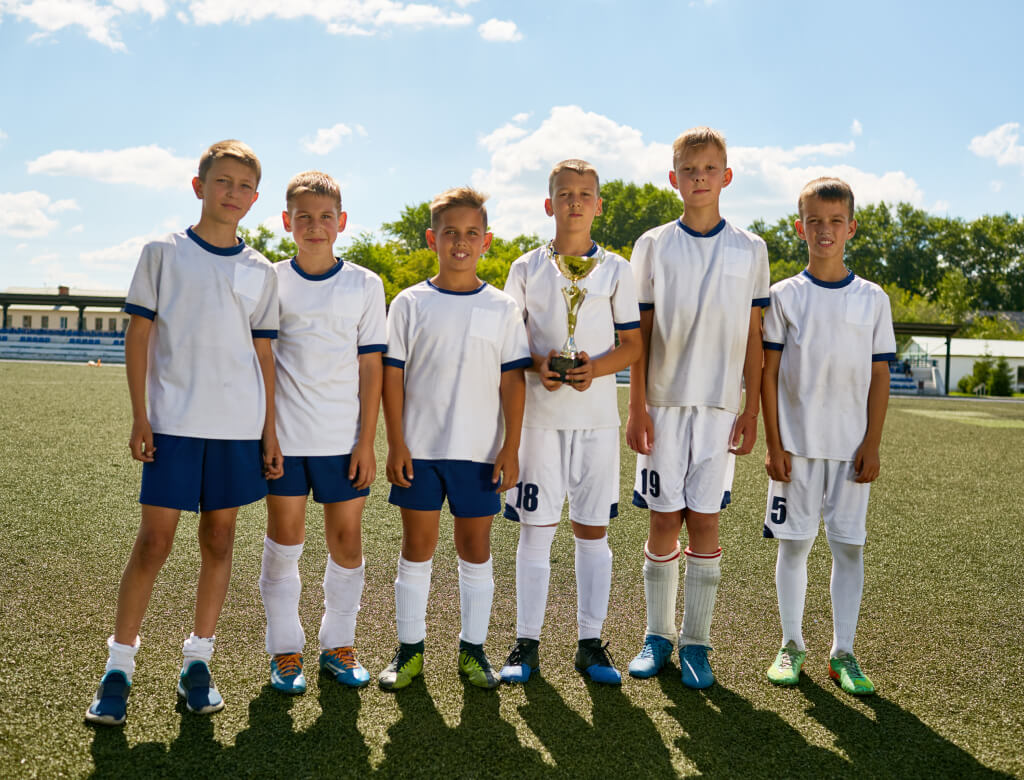 Eine Mannschaft von Jungen in Fußballtrikots steht auf einem Rasenplatz und zeigt Kameradschaft und Begeisterung für ihr bevorstehendes Spiel.