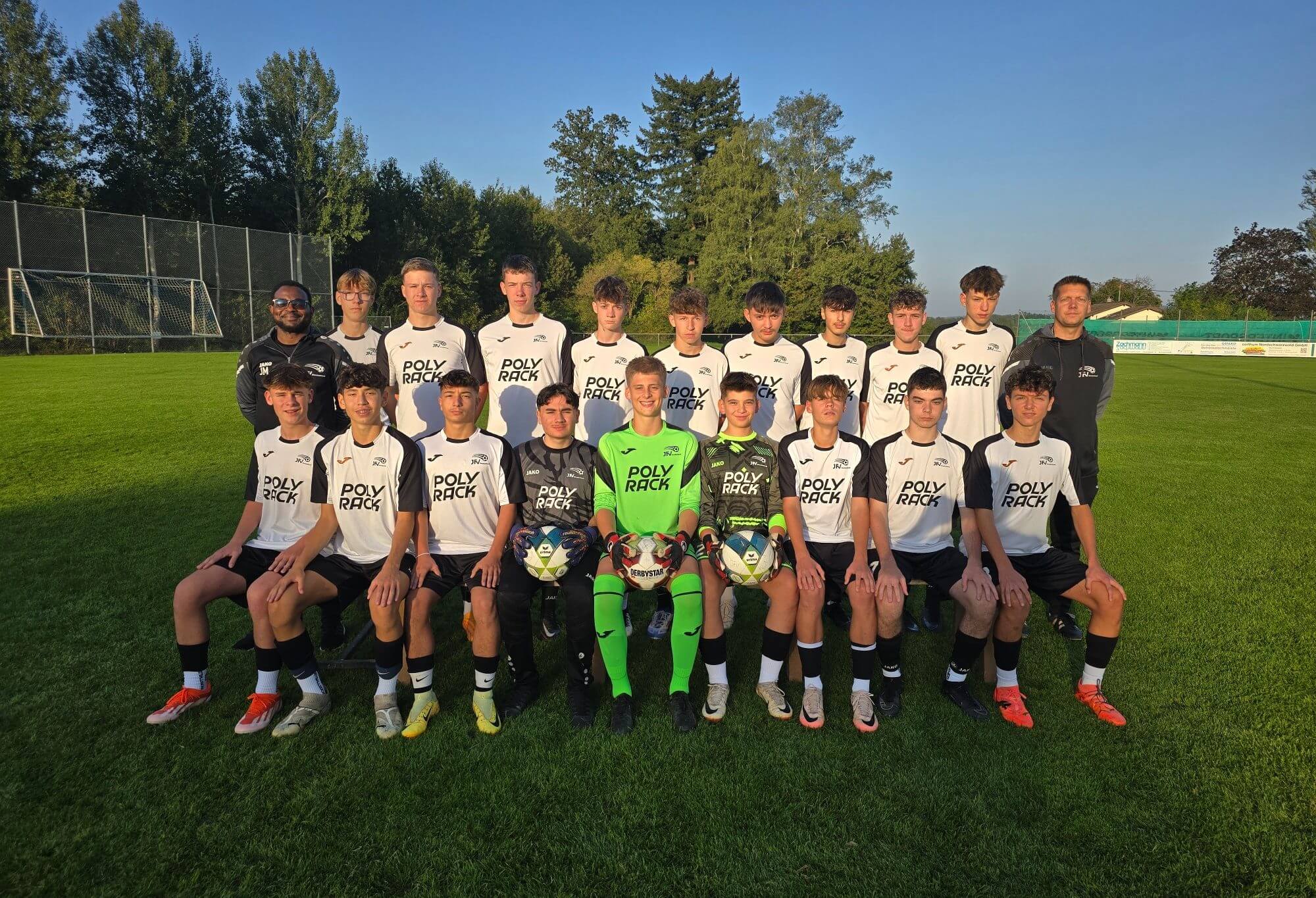 Gruppenfoto der Fußballmannschaft, die stolz auf dem Spielfeld steht und in die Kamera lächelt.