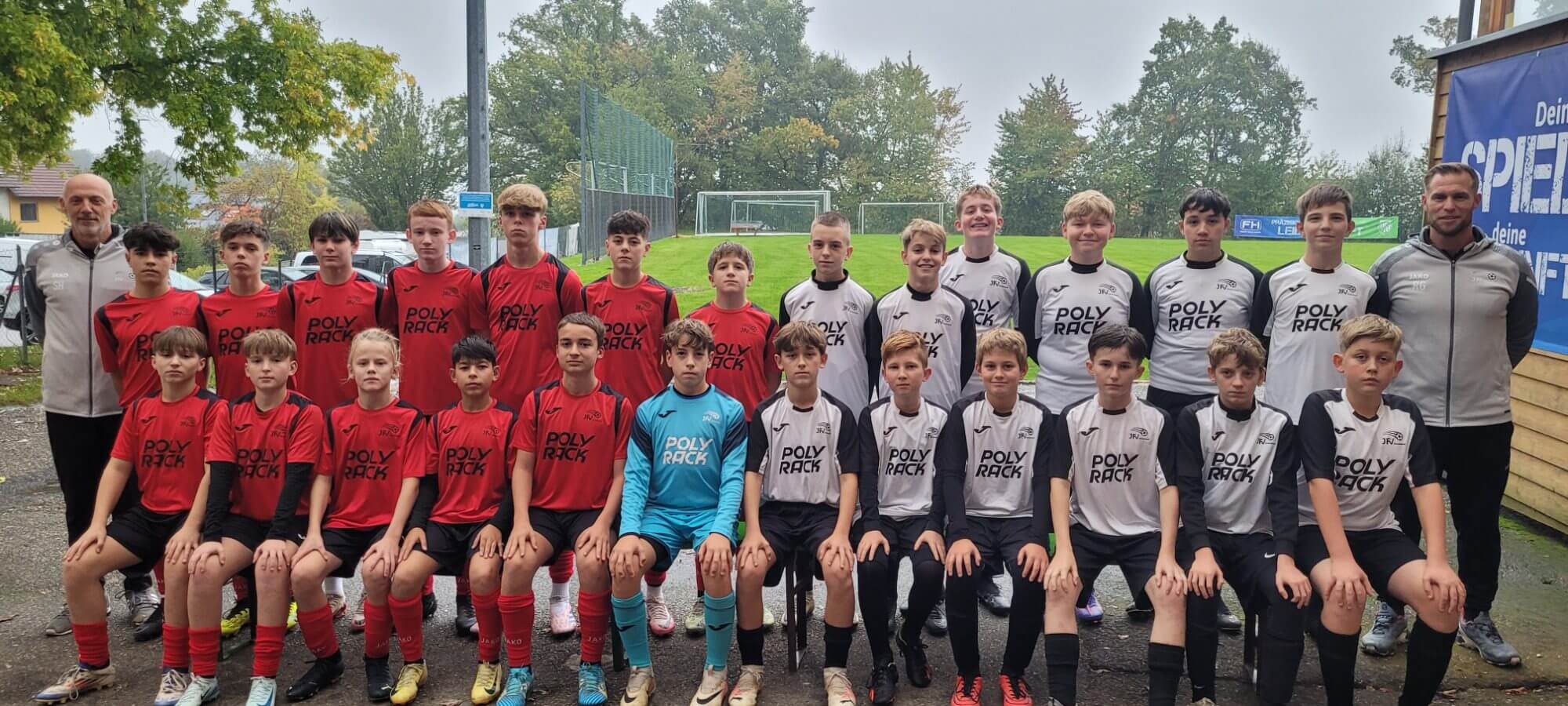 Teamfoto einer Fußballmannschaft, alle Spieler stehen zusammen und lächeln in ihren Trikots für das Gruppenbild.